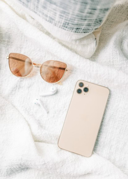 sunglasses, wireless earbuds, and phone on a blanket for a fun day outdoors